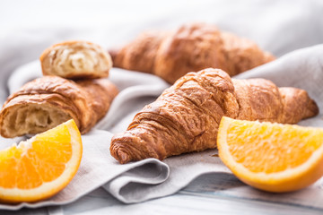Fresh buttery croisants with sweet oranges on kitchen napkin