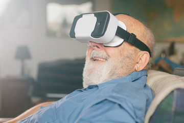 old man using virtual reality goggles at home