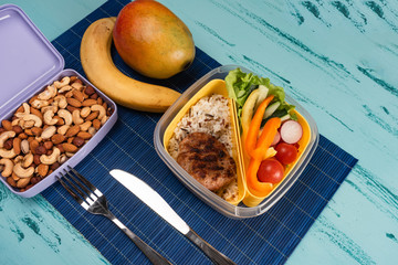 Lunch box with appetizing food and on light wooden table.