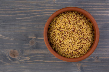 bowl of raw bulgur and quinoa on wooden table background