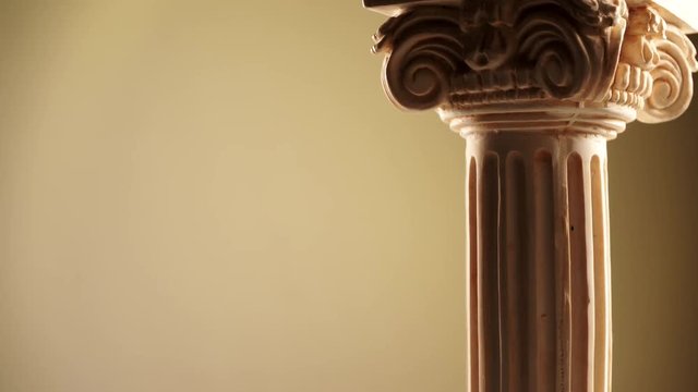 Single ancient corinthian column rotating slowly on bright background
