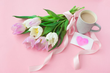 Bouquet of tulips and a coffee cup on a pink pastel background. Wonderful spring breakfast on Mother's Day or Women. Flat lay. View top. Selective focus.