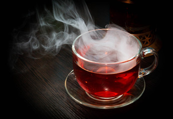hot black tea with thick steam over it on a dark wooden table
