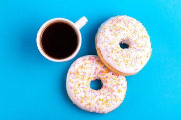 Two delicious vanilla donuts with sprinkle and cup of coffee