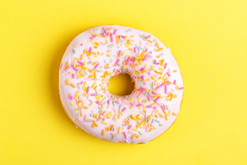 Delicious vanilla donut with sprinkle on bright yellow background