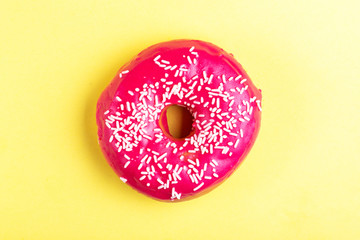 Delicious pink donut with sprinkle on bright yellow background