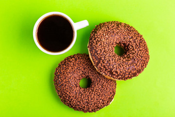 Two delicious chocolate donuts with sprinkle and cup of coffee