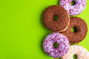 Assorted delicious donuts on bright green background