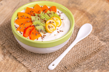 Acai bowl with vanilla smoothie, persimmon, kiwi, kumquat and flaxseeds