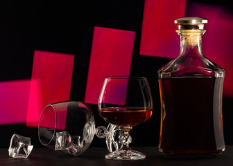 Glass and bottle of brandy on a red background