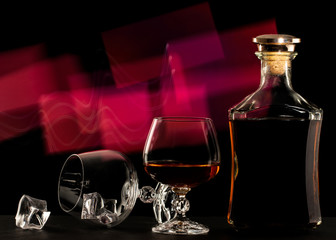 Glass and bottle of brandy on a red background