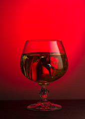A glass of brandy on a red background