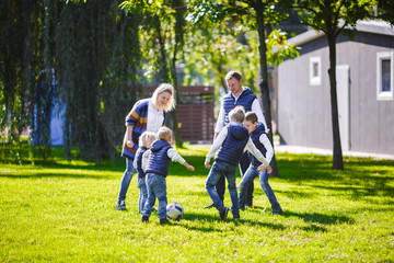 Fototapeta premium October 6, 2018 Ukraine. Kiev. theme family outdoor activities. big friendly Caucasian family six mom dad four children playing football, running ball on lawn, green grass lawn near house sunny day