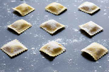 rows of raw homemade ravioli on a dark background