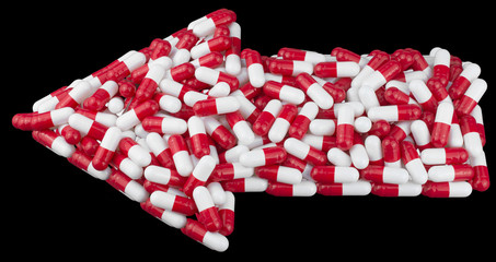 arrow made from red white medical capsules, isolated on black background. medical and pharmaceutical concept