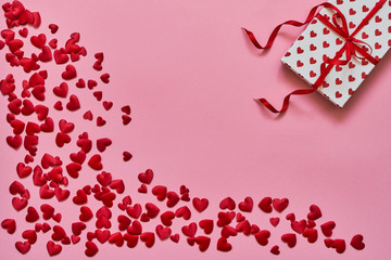 Valentines Day background. Red hearts and gift box on pink background. Copy space, top view