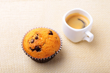 Perfect morning breakfast with Delicious homemade cupcakes with raisins, chocolate chips and espresso coffee in white cup on textile background. Muffins.