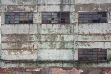 Windows and wall of the old neglected industrial building..