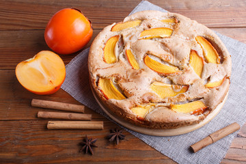 Sweet persimmon pie on brown wooden background.