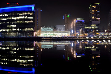 Fototapeta na wymiar Modern cityscape panorama at night. Lit buildings reflect off calm water.