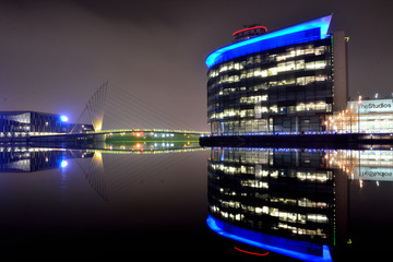 Modern cityscape panorama at night. Lit buildings reflect off calm water.