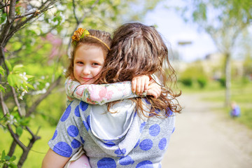 Daughter hugs mom. Happy woman holding a little girl in her arms. Beautiful mother with her daughter on Mother's Day.