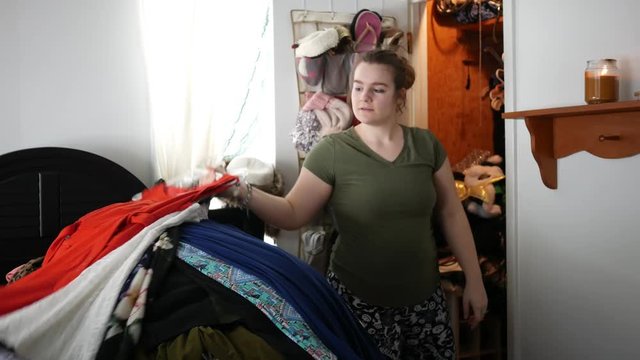 Timelapse of woman cleaning out her closet with loads of clothing on bed