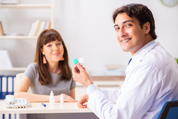 Obraz premium Young woman visiting male doctor ophthalmologist in hospital