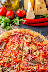 Italian pizza and ingredients on a wooden background, top view