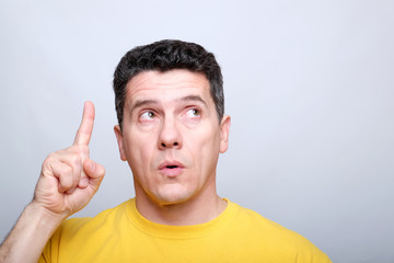 white middle-aged man raises his index finger upwards.