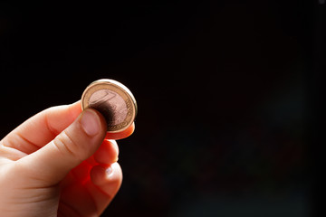 Child holding euro coin in his hand. Pocket money stock image. Poor low income group. Dark background. - Image. Close up.