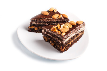Chocolate cake with caramel, peanuts and almonds isolated on a white background.