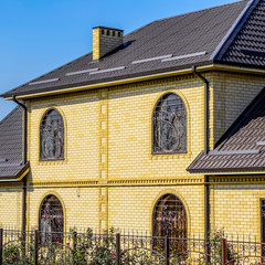 House of yellow brick and brown corrugated roof made of metal. L