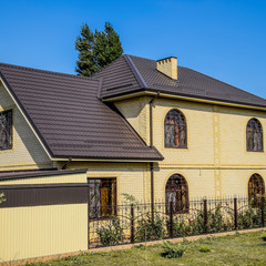 House of yellow brick and brown corrugated roof made of metal. L