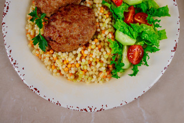Pork cutlets, couscous with vegetables and arugula.
