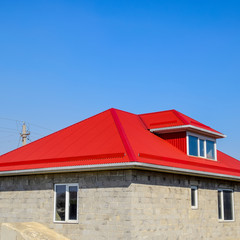 Red corrugated roof. House of cinder block. House with plastic w