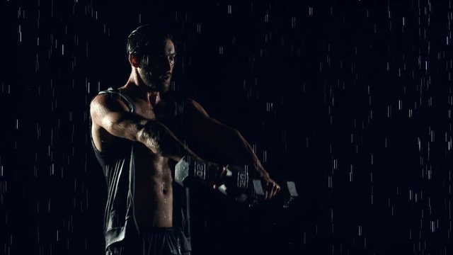 Athletic man working out in the rain. Slow Motion.