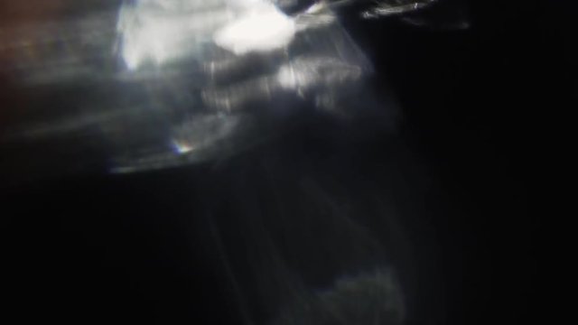 Multicolored defocused particles float in the dark, randomly changing shape. Creative transitions, glare.