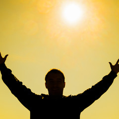 Silhouette of a man against the background of the sun and yellow