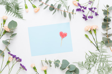 Flowers composition. Paper blank, carnation flowers, eucalyptus branches on pastel  background. Flat lay, top view, copy spaceFlat lay stiil life.