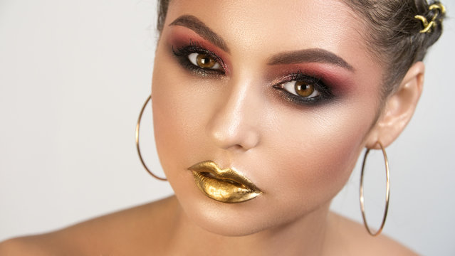 Beauty portrait of young girl with the shining smooth healthy skin of person bright expressive smoke-coloured make-up and gold on lips