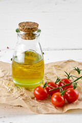 tomatoes with oil bottle on white wooden background