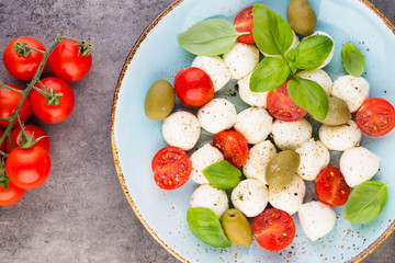Delicious caprese salad with ripe cherry tomatoes and mini mozzarella cheese balls with fresh basil leaves.