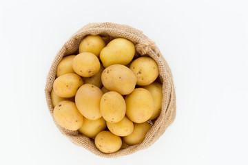 Sack of fresh raw potatoes on wooden background, top view