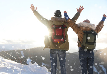 Naklejka premium Excited couple with backpacks enjoying mountain view during winter vacation. Space for text