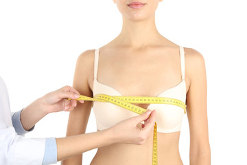 Doctor measuring size of patient's breast on white background, closeup. Cosmetic surgery