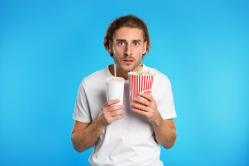 Fototapeta premium Emotional man with popcorn and beverage during cinema show on color background