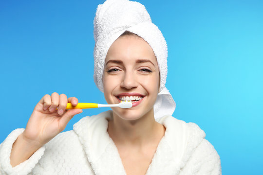 Portrait of young woman with toothbrush on color background