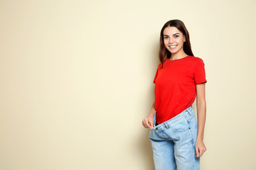 Slim woman in oversized jeans on color background, space for text. Weight loss