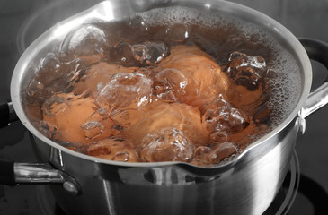 Cooking chicken eggs in pot on electric stove, closeup view